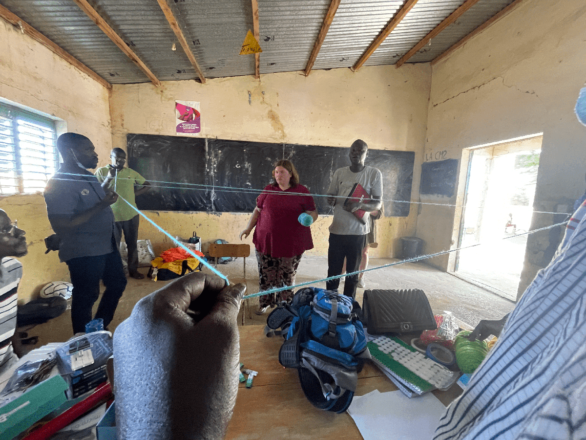 Erika Bonnett with a group of villagers using a yarn triangle to demonstrate the food chain